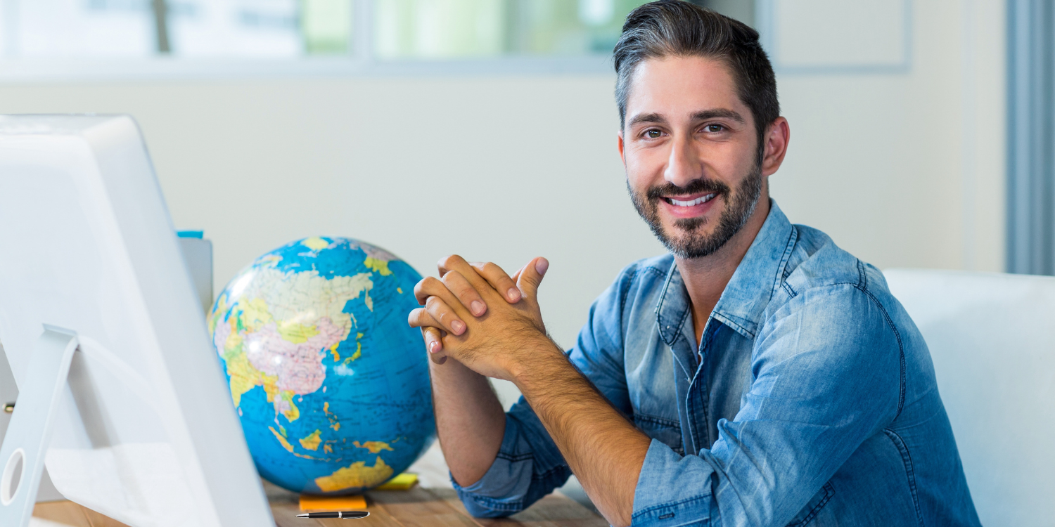 Ein Tourismusfachmann stitzt am Schreitisch und bereitet sich auf eine Ferien-Beratung vor.