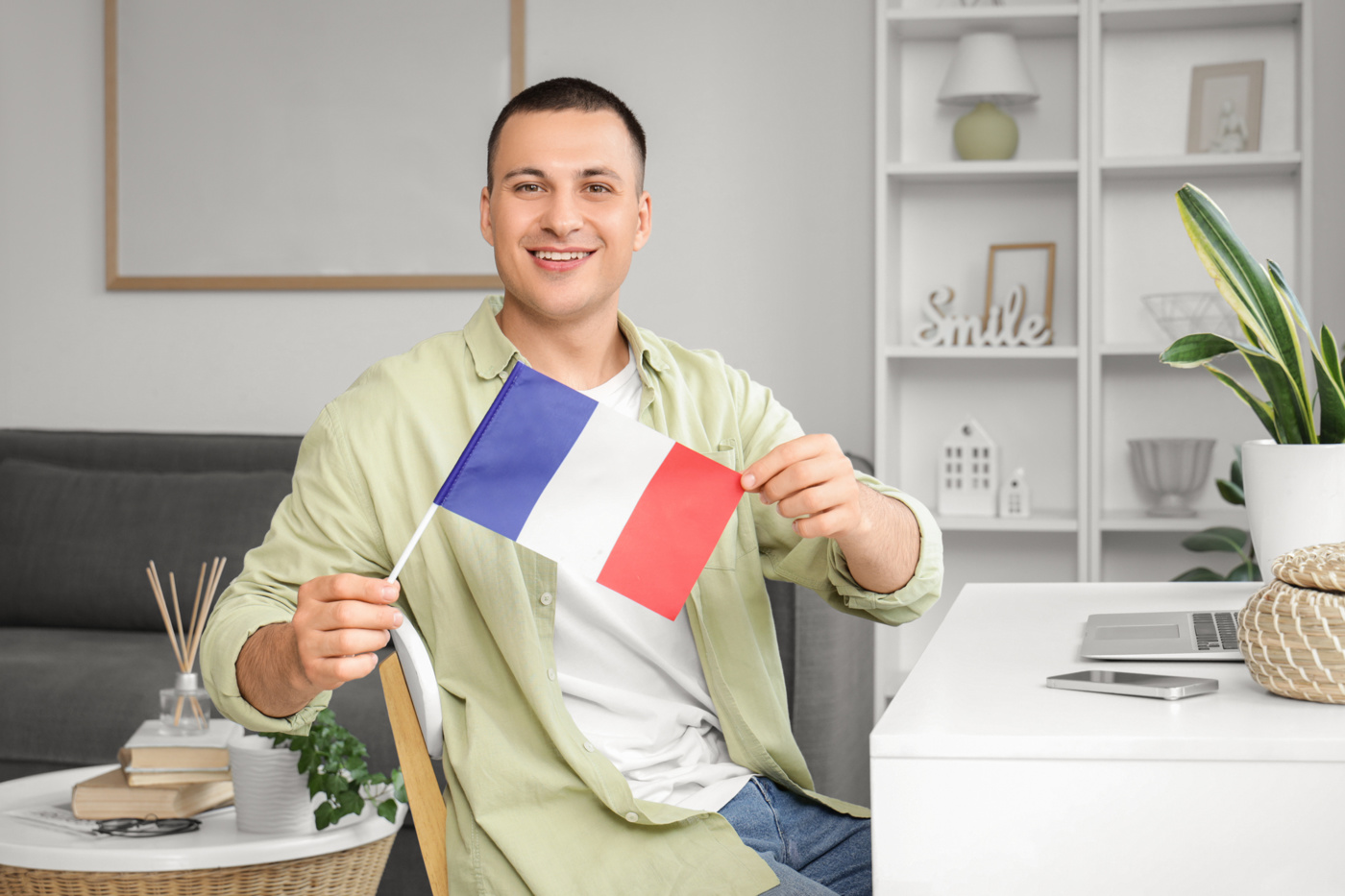 Teilnehmer an einem Französisch-Kurs online sitzt mit Fähnchen vor dem Laptop, bereit sein Französisch zu verbessern