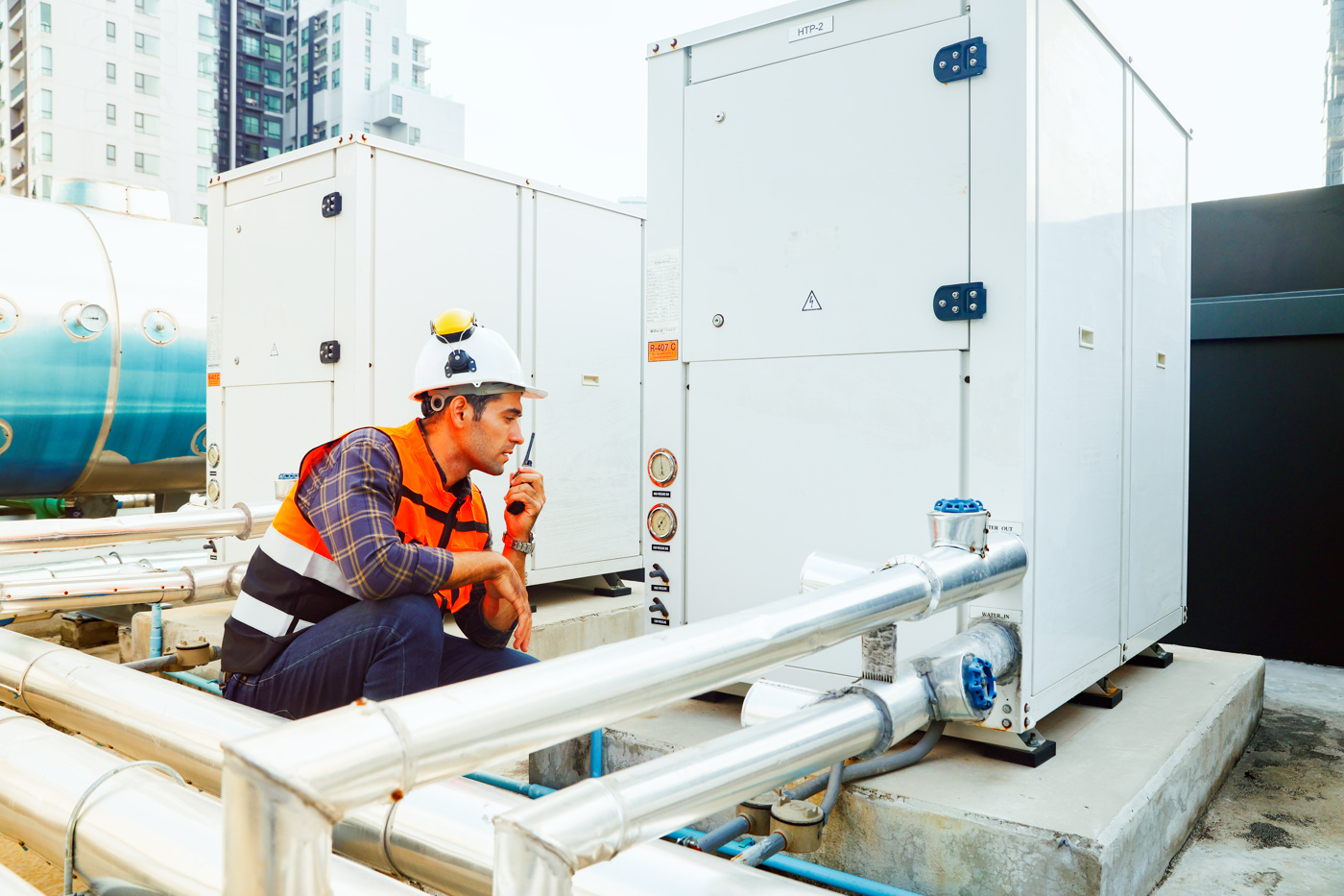 Ein Gebäudetechniker HF arbeitet an einer technischen Installation auf dem Dach von einem modernen Wohnkomplex
